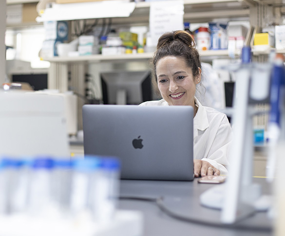 Faculty member working on laptop in research lab